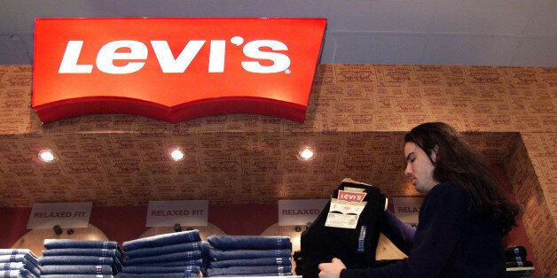 Store employee Brett Mitsobata stocks a Levi's jeans display at a downtown Toronto department store Monday, Feb. 22, 1999. Levi Strauss & Co. said Monday it would close 11 of its 22 plants in North America and lay off about 5,900 employees, or 30 percent of its work force in the United States and Canada. (AP Photo/CP Kevin Frayer)
