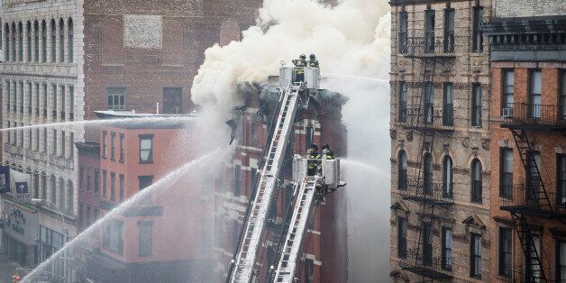New York City firefighters work the scene of a large fire and a partial building collapse in the East Village neighborhood of New York on Thursday, March 26, 2015. Orange flames and black smoke are billowing from the facade and roof of the building near several New York University buildings. (AP Photo/John Minchillo)