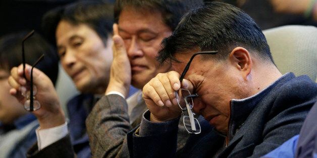 In this Friday, Nov. 7, 2014 photo, family members of passengers aboard the sunken ferry Sewol wipe their tears after South Korean lawmakers voted during the plenary session at the National Assembly in Seoul, South Korea. South Korea's National Assembly on Friday approved plans to disband the coast guard in the wake of criticism over its failure to rescue hundreds of passengers during the sinking of a ferry in April. (AP Photo/Lee Jin-man)