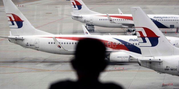 A man views a fleet of Malaysia Airline planes on the tarmac of the Kuala Lumpur International Airport, in Malaysia, Thursday, Jan. 29,  2015. Malaysia's Civil Aviation Authority officially declared the MH370 crash an accident on Thursday, fulfilling a legal obligation that will allow efforts to proceed with compensation claims. (AP Photo/Joshua Paul)