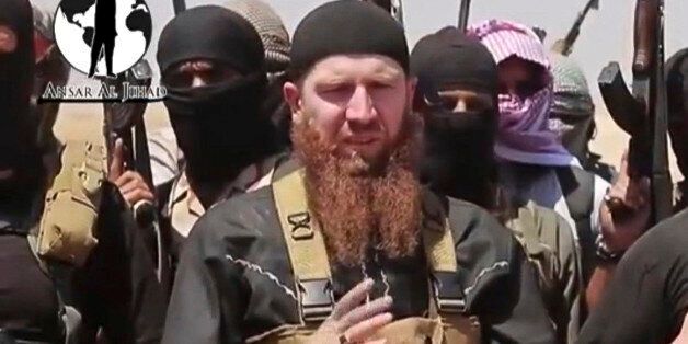 This image made from undated video posted during the weekend of June 28, 2014 on a social media account frequently used for communications by the Islamic State of Iraq and the Levant (ISIL), which has been verified and is consistent with other AP reporting, shows Omar al-Shishani standing next to the group's spokesman among a group of fighters as they declare the elimination of the border between Iraq and Syria. Al-Shishani, one of hundreds of Chechens who have been among the toughest jihadi fig