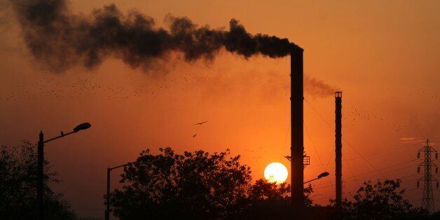 Birds fly past at sun set as smoke emits from a chimney at a factory in Ahmadabad, India, Monday, Dec. 8, 2014. The momentum from a historic U.S.-China pact to resist global warming is showing signs of fading at the U.N. climate talks in Peru as the familiar rich-poor conflict persists over who should do what to keep the planet from overheating. The conference's high-level phase begins Tuesday. (AP Photo/Ajit Solanki)