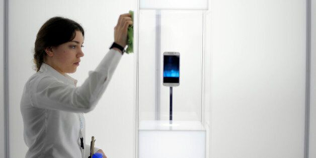 A woman cleans a glass cabinet containing the new Galaxy S6 smartphone during the Mobile World Congress, the world's largest mobile phone trade show in Barcelona, Spain, Tuesday, March 3, 2015. (AP Photo/Manu Fernandez)