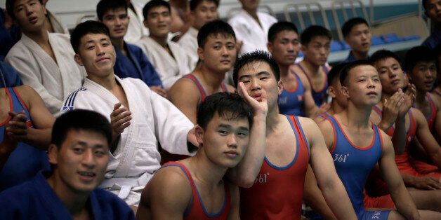 North Korean athletes cheer on their teammate as he wrestles with a pro wrestler Friday, Aug. 29, 2014 in Pyongyang, North Korea. Former NFL player Bob