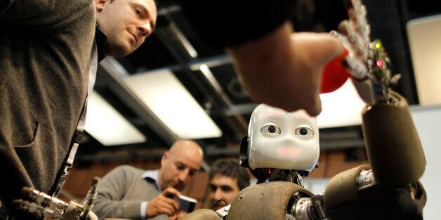 People look at the iCub robot during the Innorobo European summit, an event dedicated to the service robotics industry, in Lyon, central France, Thursday, March 15, 2012. The iCub robot, created by the Italian Institute of Technology, is used for research into human cognition and artificial intelligence. (AP Photo/Laurent Cipriani)