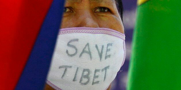 An Exile Tibetan woman covers her face with a mask which reads