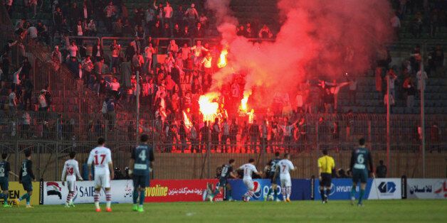 Soccer fans hold lit flares at the stand as they watch a match between Egyptian Premier League clubs Zamalek and ENPPI at Air Defense Stadium in a suburb east of Cairo, Egypt, Sunday, Feb. 8, 2015. A riot broke out Sunday night outside of the major soccer game, with a stampede and fighting between police and fans killing at least 22 people, authorities said. (AP Photo/Ahmed Abd El-Gwad, El Shorouk newspaper) EGYPT OUT