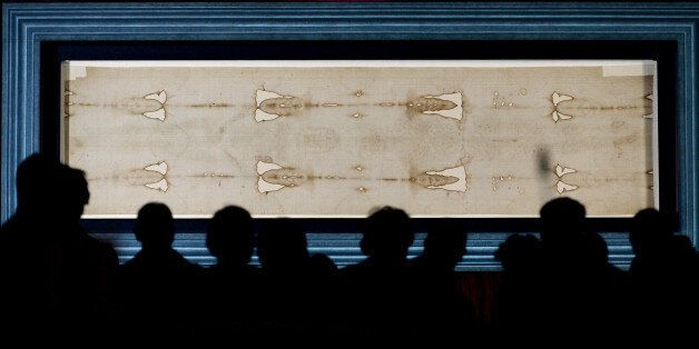 People admire the Holy Shroud, the 14 foot-long linen revered by some as the burial cloth of Jesus, on display at the Cathedral of Turin, Italy, Sunday, April 19, 2015. The long linen with the faded image of a bearded man, that is the object of centuries-old fascination and wonderment, will be on display for the public from April 19 to June 24, 2015. Pope Francis said he is planning to visit the Holy Shroud during a a pilgrimage to Turin next June 21, 2015. (AP Photo/Massimo Pinca)