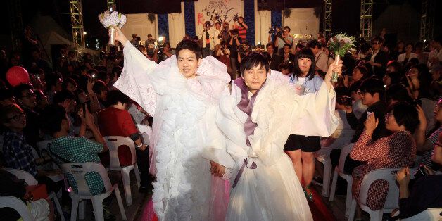 South Korean movie director Kim Jho Gwangsoo, right, and his partner Dave Kim march after their wedding ceremony in Seoul, South Korea, Saturday, Sept. 7, 2013. Director Kim surprised many in May, 2013, by announcing he will symbolically tie the knot with his longtime male partner Sept. 7, in the highest-profile ceremony of its kind ever in South Korea. (AP Photo/Ahn Young-joon)