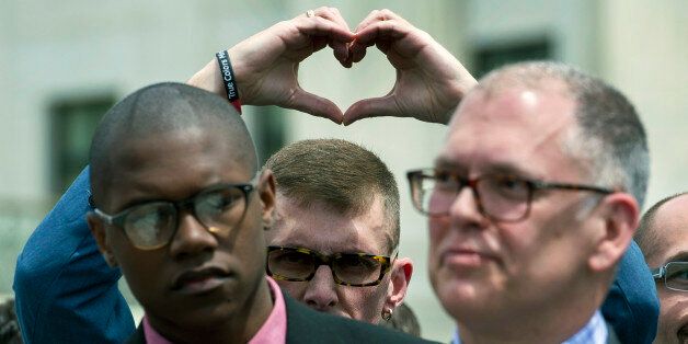 Plaintiff Rev. Maurice Blanchard, of Louisville, Ky., makes heart with his hands behind plaintiff plaintiff James Obergefell of Ohio, right, as they stand outside of the Supreme Court in Washington, Tuesday, April 28, 2015, following a hearing on same-sex marriages. (AP Photo/Cliff Owen)