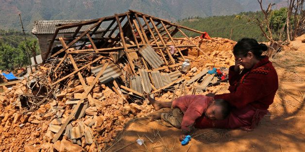 A Nepalese woman sits with her son near their house, destroyed in last week's earthquake, in Pauwathok village, Sindhupalchok district, Nepal, Saturday, May 2, 2015. Life has been slowly returning to normal in Kathmandu, but to the east, angry villagers in parts of the Sindhupalchok district said Saturday they were still waiting for aid to reach them. In the village of Pauwathok, where all but a handful of the 85 houses were destroyed, three trucks apparently carrying aid supplies roared by with