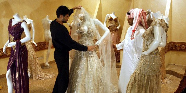 A Saudi man, right, buys a wedding dress at a shop in Riyadh, Saudi Arabia, Sunday, Aug. 3, 2008. The recent spate of marriages involving boys and girls married off to each other by their fathers or of girls given away to much older men has been widely denounced by Saudi human rights groups, clerics and writers who say such unions are harmful to the children and trivialize the institution of marriage. (AP Photo)