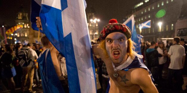 A supporter of the Yes campaign in the Scottish independence referendum pulls a face in good humor as he reacts to being photographed as people gather together after the polls closed, in George Square, Glasgow, Scotland, late Thursday, Sept. 18, 2014.  From the capital of Edinburgh to the far-flung Shetland Islands, Scots embraced a historic moment - and the rest of the United Kingdom held its breath - after voters turned out in unprecedented numbers for an independence referendum that could end