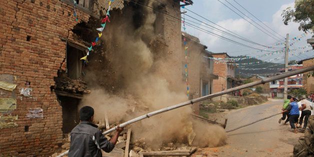 The walls of a damaged home crumble as it is knocked down by people in Lalitpur, Nepal, Friday, May 8, 2015. The April 25 earthquake killed thousands and injured many more as it flattened mountain villages and destroyed buildings and archaeological sites in Kathmandu. (AP Photo/Niranjan Shrestha)