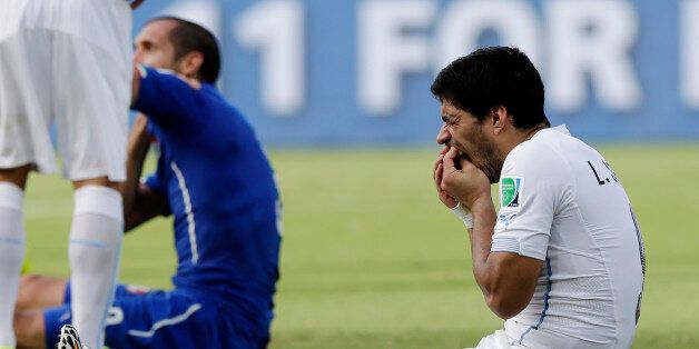 Uruguay's Luis Suarez holds his teeth after running into Italy's Giorgio Chiellini's shoulder during the group D World Cup soccer match between Italy and Uruguay at the Arena das Dunas in Natal, Brazil, Tuesday, June 24, 2014. (AP Photo/Ricardo Mazalan)