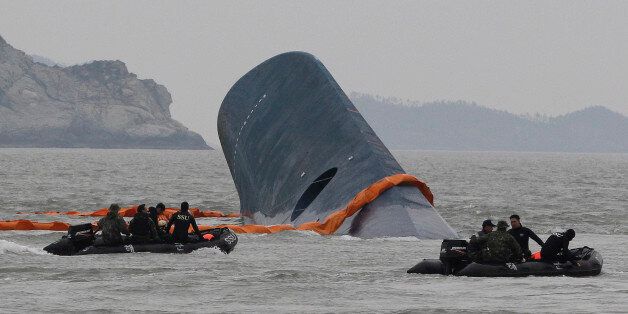 FILE - In this April 17, 2014 file photo, South Korean Coast Guard officers search for missing passengers aboard sunken ferry Sewol in the waters off the southern coast near Jindo, South Korea. One month after the ferry sinking that left more than 300 people dead or missing, there is a national debate - and spasms of shame and fury - over issues neglected as the country made its breakneck way from poverty, war and dictatorship to one of Asiaâs top economic, diplomatic and cultural powers. T