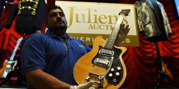 An employee of Julien's Auctions shows musician George Harrison's Mastersound Electric Guitar before the auction start at the Hard Rock Cafe in New York on May 15, 2015. The guitar played by Harrison in the Beatles' early days, previously on display in a British museum, goes on auction in New York on May 15, valued at $400,000 to $600,000 USD. The electric guitar is the two-day auction's star item, amid hundreds of possessions once owned by rock 'n' roll's biggest stars, which auctioneers hope w