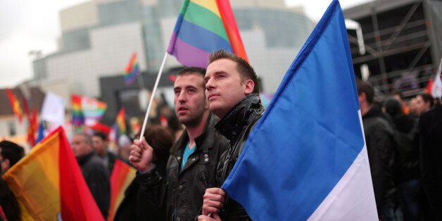 People holding the French and the rainbow flags attend the event