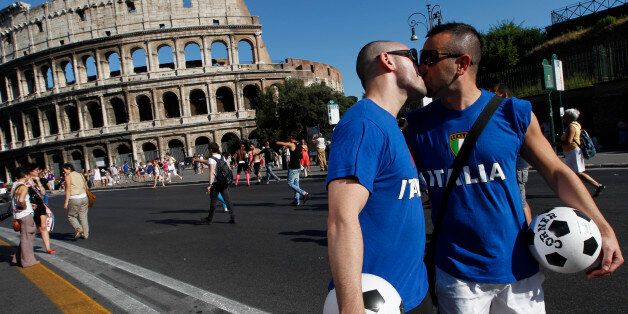 A couple wearing Italy's national soccer team t-shirts kiss during a Gay Pride Parade as the demonstration marches past the ancient Colosseum in Rome, Saturday, June 23, 2012. (AP Photo/Alessandra Tarantino)