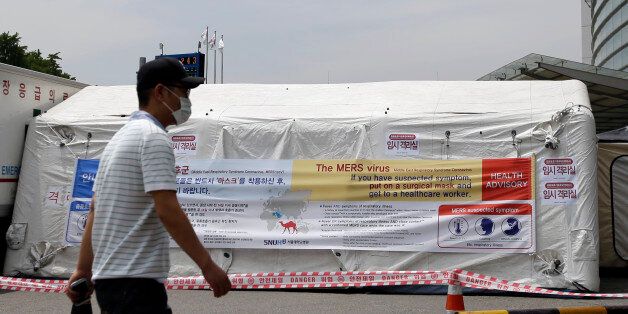 A man wearing mask walks near a precaution against the MERS, Middle East Respiratory Syndrome, virus at a quarantine tent for people who could be infected with the MERS virus at Seoul National University Hospital in Seoul, South Korea, Tuesday, June 2, 2015. South Korea on Tuesday confirmed the country's first two deaths from MERS as it fights to contain the spread of the virus that has killed hundreds of people in the Middle East. (AP Photo/Lee Jin-man)