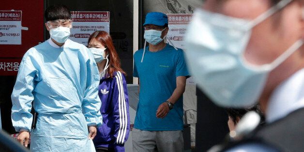 Hospital workers and visitors wearing masks pass by a precaution against the MERS, Middle East Respiratory Syndrome, virus at a quarantine tent for people who could be infected with the MERS virus at Seoul National University Hospital in Seoul, South Korea, Wednesday, June 3, 2015. South Korea on Tuesday confirmed the country's first two deaths from MERS as it fights to contain the spread of a virus that has killed hundreds of people in the Middle East.(AP Photo/Ahn Young-joon)