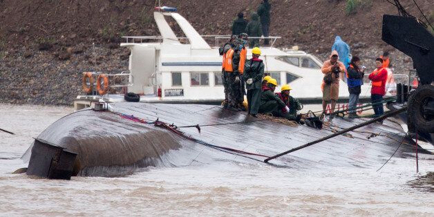 Chinese soldiers stand as rescuers conduct a search and rescue operation on the capsized ship, center, on the Yangtze River in central China's Hubei province Wednesday, June 3, 2015. Hopes dimmed Wednesday for rescuing more than 400 people still trapped in a capsized river cruise ship that overturned in stormy weather, as hundreds of rescuers searched the Yangtze River site in what could become the deadliest Chinese maritime accident in decades. (AP Photo/Andy Wong)
