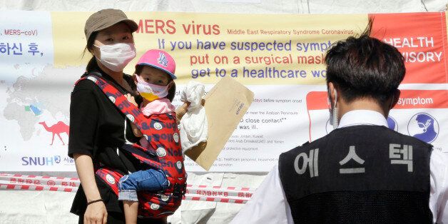 A mother and her daughter wearing masks walk near a precaution against the MERS, Middle East Respiratory Syndrome, virus at a quarantine tent for people who could be infected with the MERS virus at Seoul National University Hospital in Seoul, South Korea, Wednesday, June 3, 2015. South Korea on Tuesday confirmed the country's first two deaths from MERS as it fights to contain the spread of a virus that has killed hundreds of people in the Middle East.(AP Photo/Ahn Young-joon)