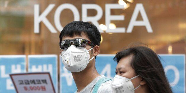 A couple wears masks as a precaution against the Middle East Respiratory Syndrome (MERS) virus as they walk in Myeongdong, one of Seoul's main shopping districts, Monday, June 15, 2015. After a weeklong review of the outbreak of Middle East respiratory syndrome, experts from WHO and South Korea told reporters Saturday there was no evidence to suggest the virus, currently confined around health facilities, is spreading. (AP Photo/Ahn Young-joon)