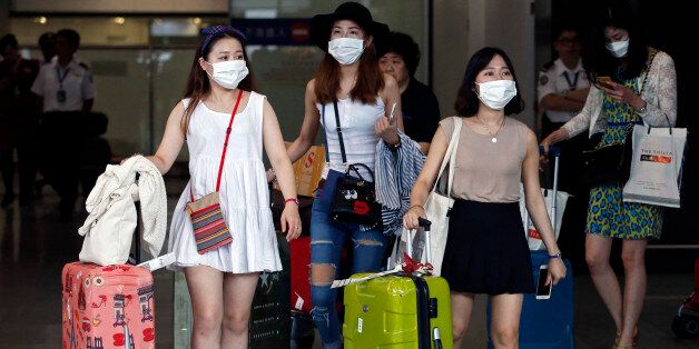 Passengers flying from Seoul, South Korea, wear masks as a precaution against MERS, Middle East Respiratory Syndrome, as they arrive at Hong Kong Airport Tuesday, June 9, 2015.  The Hong Kong government on Tuesday issued a red travel alert for South Korea because of the current MERS outbreak in the country. (AP Photo/Kin Cheung)