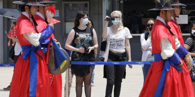 Tourists wearing masks as a precaution against MERS, Middle East Respiratory Syndrome, virus watch a ceremony at the Gyeongbok Palace, one of South Korea's well-known landmarks, in Seoul, South Korea, Sunday, June 7, 2015. A fifth person in the country has died of the MERS virus, as the government announced Sunday it was strengthening measures to stem the spread of the disease and public fear. (AP Photo/Lee Jin-man)