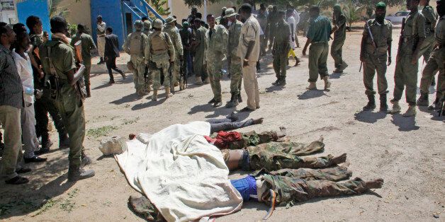 Somali soldiers look at the bodies of suspected attackers after a car bomb that was detonated at the gates of a government office complex in the capital Mogadishu, Somalia, Tuesday, April 14, 2015. A number of people were killed on Tuesday when attackers stormed the ministry of higher education after a suicide car bomber detonated his vehicle at the gate of the office complex, opening the way for gunmen to enter, according to a senior police officer. (AP Photo/Farah Abdi Warsameh)