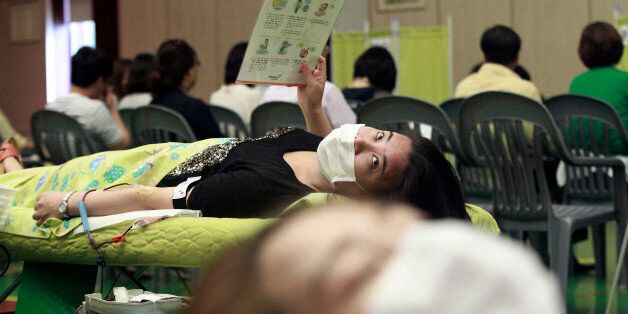 Officials wear masks as a precaution against the MERS (Middle East Respiratory Syndrome) as they lie to donate their blood at Dongdaemun District Office in Seoul, South Korea, Thursday, June 18, 2015. Blood donations have been halted en masse in recent weeks due to the outbreak of MERS, which has raised concerns about available stockpiles at blood center nationwide. (AP Photo/Ahn Young-joon)
