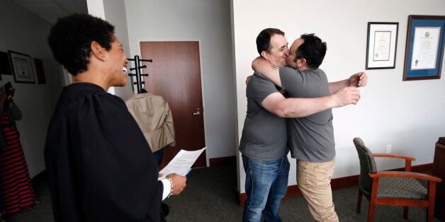 Judge Tonya Parker with the 116th District Court smiles as she watches Kenneth Denson, left, and Gabriel Mendez, right, kiss after the two were married during a private ceremony in Judge Parker's chambers Friday, June 26, 2015, in Dallas. (Same-sex couples won the right to marry nationwide Friday as a divided Supreme Court handed a crowning victory to the gay rights movement, setting off a jubilant cascade of long-delayed weddings in states where they had been forbidden. (AP Photo/Tony Gutierrez