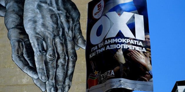 Hands painted on the wall of a building seen behind a poster for a NO vote in the upcoming referendum, in central Athens, Wednesday, July 1, 2015. European officials and Greek opposition parties have been adamant that a
