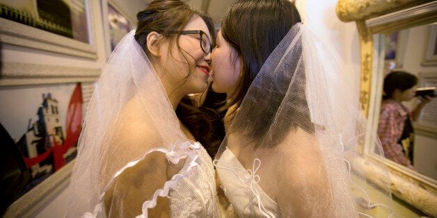 Teresa Xu, left, and Li Tingting, right, share a kiss in a beauty salon where the two were preparing for their wedding in Beijing, Thursday, July 2, 2015. A prominent Chinese lesbian couple held a simple ceremony Thursday to announce their informal marriage, in their latest effort to push for legalization of same-sex unions in China. (AP Photo/Mark Schiefelbein)