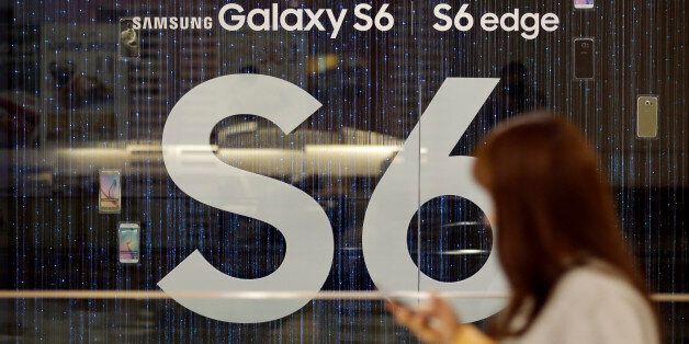 A woman walks by the advertisement of Samsung's Galaxy S6 smartphone outside its showroom in Seoul, South Korea, Wednesday, April 29, 2015. Samsung Electronics Co. said its first-quarter net income plunged 39 percent as consumers switched to bigger iPhones, squeezing its profit from the mobile business to less than half from a year earlier. (AP Photo/Lee Jin-man)