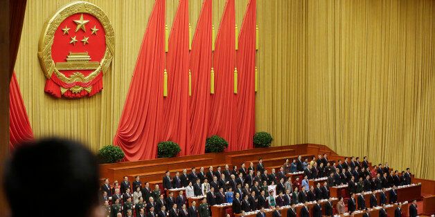 Delegates stand to listen to the Chinese national anthem during the opening session of the National People's Congress at the Great Hall of the People in Beijing Thursday, March 5, 2015. China announced a lower economic growth target for this year and promised to open more industries to foreign investors as it tries to make its slowing, state-dominated economy more productive. (AP Photo/Andy Wong)