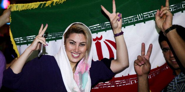 An Iranian woman shows the victory sign as people celebrate on a street following a landmark nuclear deal, in Tehran, Iran, Tuesday, July 14, 2015. Overcoming decades of hostility, Iran, the United States, and five other world powers struck a historic accord Tuesday to check Tehran's nuclear efforts short of building a bomb. The agreement could give Iran access to billions in frozen assets and oil revenue, stave off more U.S. military action in the Middle East and reshape the tumultuous region.