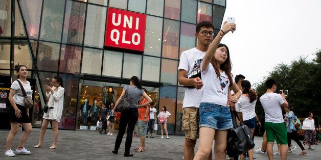 A Chinese couple take a selfie outside the Uniqlo flagship store where a steamy video purportedly taken inside one of its fitting room showing a couple apparently having sex in Beijing, Thursday, July 16, 2015. While online searches for the Japanese clothing brand soared after the viral spread of the video, it has also drawn the concern of the police and China's highest web regulator who are investigating whether it was a vulgar marketing gimmick. (AP Photo/Ng Han Guan)