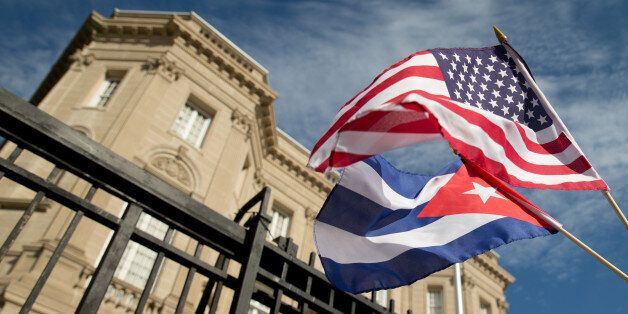 Edwardo Clark, a Cuban-American, holds an American flag and a Cuban flag as he celebrates outside the new Cuban embassy in Washington, Monday, July 20, 2015. The United States and Cuba restored full diplomatic relations Monday after more than five decades of frosty relations rooted in the Cold War. (AP Photo/Andrew Harnik)