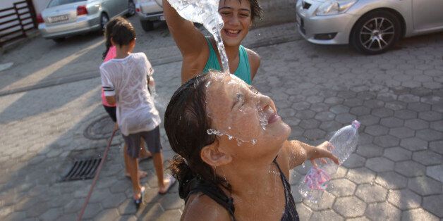 Children pour water over each other as they try to refresh themselves on a hot day in Hajvali 15 km (12 miles) from capital Pristina on Sunday, July 19, 2015. Europe's heat wave has pushed the mercury to levels as high as 40 degrees Celsius, 104 fahrenheit . (AP Photo/Visar Kryeziu)