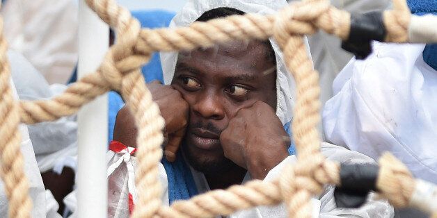 A migrant shelters from rain as he waits to disembark from Italian Coast Guard ship Oreste Corsi, at the Messina harbor in Sicily, Italy, Tuesday, Aug. 4, 2015. Italyâs Coast Guard rescued 306 migrants on Tuesday, and took them safely to land in Messina as the migrants death toll for 2015 reached in August over 2000 victims, and IOM called the Channel of Sicily the deadliest route for migrants in search of a better life. (AP Photo/Carmelo Imbesi)