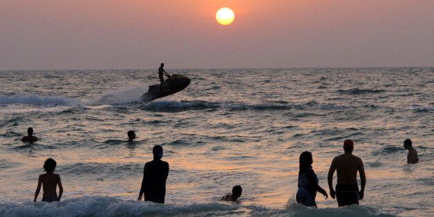 People enjoy a sunset swim at a public beach in Dubai, United Arab Emirates, Thursday, Sept. 6, 2012. (AP Photo/Hassan Ammar)