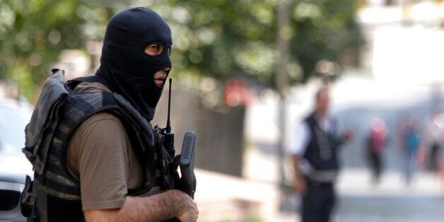 A masked Turkish police officer secures a road leading to the U. S. Consulate building in Istanbul, Monday, Aug. 10, 2015. Two assailants opened fire at the building on Monday, touching off a gunfight with police before fleeing the scene, Turkish media reports said. (AP Photo/Lefteris Pitarakis)