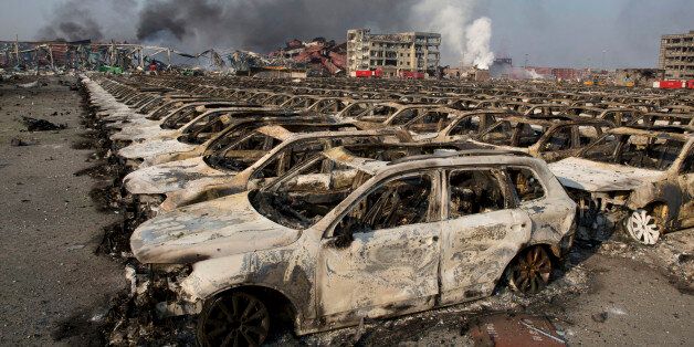 Smoke billows from the site of an explosion that reduced a parking lot filled with new cars to charred remains at a warehouse in northeastern China's Tianjin municipality, Thursday, Aug. 13, 2015. Huge, fiery blasts at a warehouse for hazardous chemicals killed many people and turned nearby buildings into skeletal shells in the Chinese port of Tianjin, raising questions Thursday about whether the materials had been properly stored. (AP Photo/Ng Han Guan)