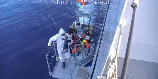 This image taken from video provided by the Italian Navy (Marina Militare) Saturday, Aug. 15, 2015, shows migrants boarding a navy vessel after being rescued from a fishing boat, off the coast of Libya. At least 40 migrants died on Saturday in the hold of an overcrowded smuggling boat in the Mediterranean Sea north of Libya, apparently killed by fuel fumes. Some 320 others on the same boat were saved by the Italian navy, the rescue ship's commander said. Migrants by the tens of thousands are bra