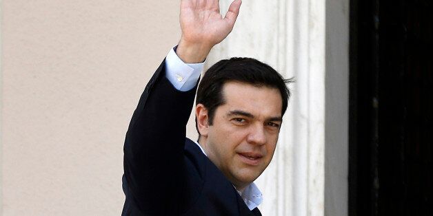 Greece's Prime Minister Alexis Tsipras waves to the media as he arrives at Maximos Mansion after a swearing in ceremony of his new ministers in Athens, Saturday, July 18, 2015. Tsipras reshuffled his Cabinet on Friday following a rebellion within his party over a parliamentary vote to approve the measures demanded for the bailout talks to start. Greek parliament approved creditor's demand for austerity measures. (AP Photo/Thanassis Stavrakis)