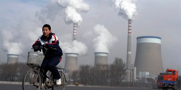A Chinese boy cycles past a cooling towers of a coal-fired power plant in Dadong, Shanxi province, China, Thursday, Dec. 3, 2009. The U.N.'s environment chief said Tuesday he is optimistic that the climate change talks beginning in Copenhagen next week will reach a deal setting firm targets to cut carbon emissions. (AP Photo/Andy Wong)