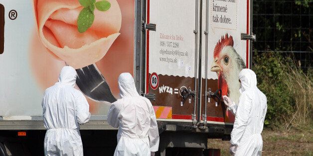 Investigators stand near a  truck that  stands on the shoulder of the highway A4 near Parndorf south of Vienna, Austria, Thursday, Aug 27, 2015. At least 20 migrants were found dead in the truck parked on the Austrian highway leading from the Hungarian border, police said. (AP Photo/Ronald Zak)