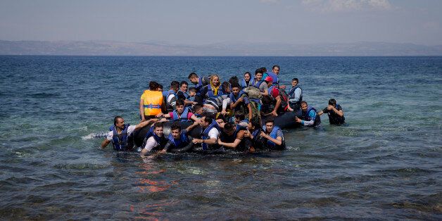 Refugees and migrants arrive on a dinghy after crossing from Turkey to Lesbos island, Greece, Friday, Sept. 11, 2015. While migrants for years have taken death-defying trips across the Mediterranean to reach the relative peace and comfort of the Europe Union, the flow has hit record proportions this year _ notably with an influx of Syrians, Afghans and Eritreans fleeing trouble back home.(AP Photo/Petros Giannakouris)